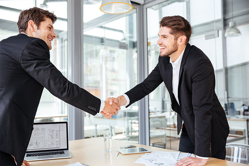 two-cheerful-businessmen-shaking-hands-on-business-PTBLS2E.jpg